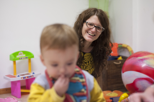 mother smiles her child as he plays early stimulation session