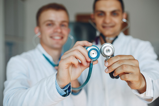 Doctors   holding a stethoscope. Students practice medicine. Man  in medical gowns. Nurse looks at the camera.