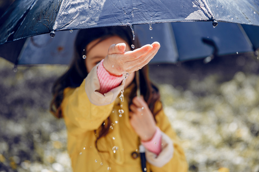 Little girl in a rain coat. Child playing in a park. 