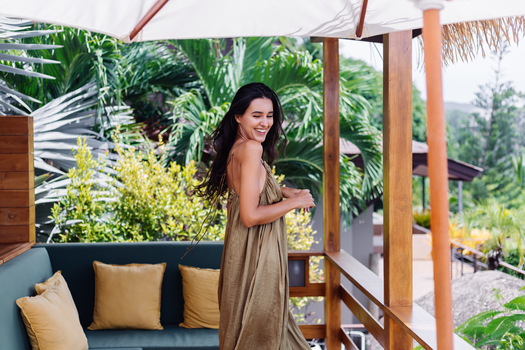 pretty european positive smiling woman summer flying dress natural day light villa terrace enjoying beautiful vacation outdoor sofa with pillows tropical