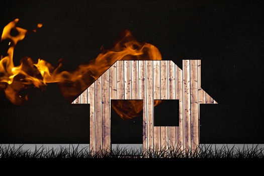 composite of burning house graphic on black grass