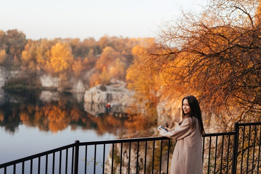Beautiful elegant woman in a park at the background is a lake