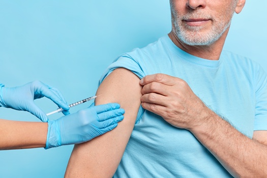 Faceless doctor makes covid 19 vaccine injection to elderly patient wears protective rubber gloves. Unknown senior male model being immunized against coronavirus. Medical treatment against pandemic