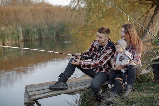 Family by the river. Guy in a red shirt. Father with little son in a fishing.