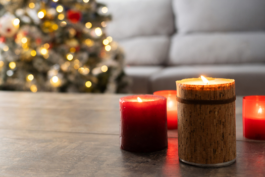 Red Christmas candles with holiday lights and christmas tree in background