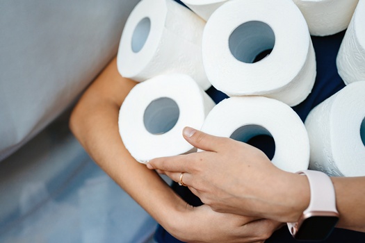 People are stocking up toilet paper for home quarantine from coronavirus. Woman holds many rolls of toilet paper