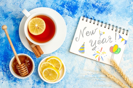 top view cup tea new year written notepad lemon slices honey bowl blue table