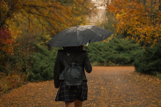 woman with umbrella walking park rainy autumn day