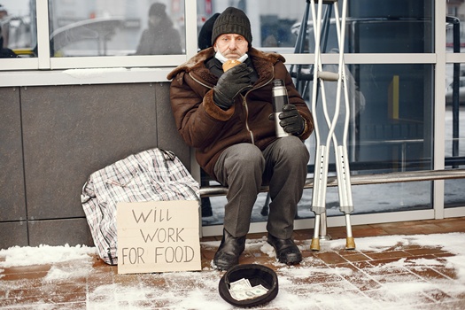 Homeless sitting near building. Disabled with crutches. Man asking for food. Man with a tablet.