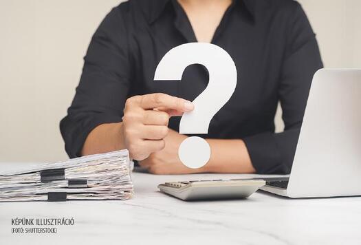 Question mark symbol. Business people in black shirt hold a white question mark symbol sitting at the table. Close-up photo. Space for text