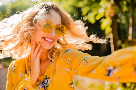 portrait of beautiful blond stylish smiling woman in yellow blouse wearing sunglasses making selfie photo, colorful autumn fashion trend, bright sunny day, positive happy mood
