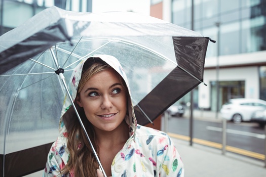 Beautiful woman holding umbrella during rainy season