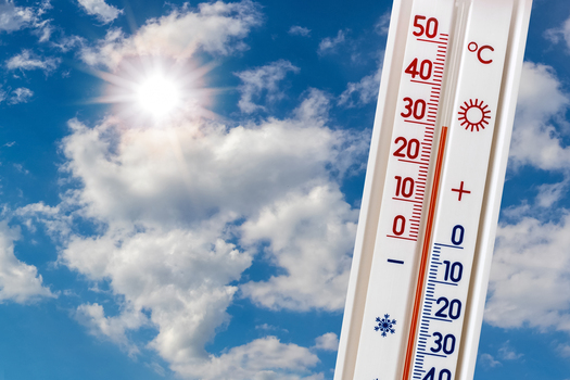 Thermometer on a background of blue sky with white clouds and the sun shows 30 degrees of heat. Summer heat